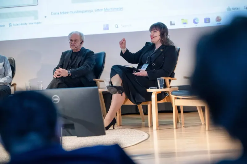 Kalbu diskusijoje su mikrofonu ant galvos, šalia sėdi kitas diskusijos dalyvis