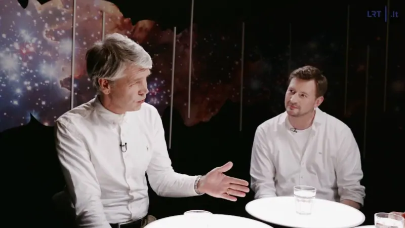 Jonas Dagys kalba rodydamas ranka, Aivaras Vilutis klausosi – už jų žvaigždėto dangaus fonas