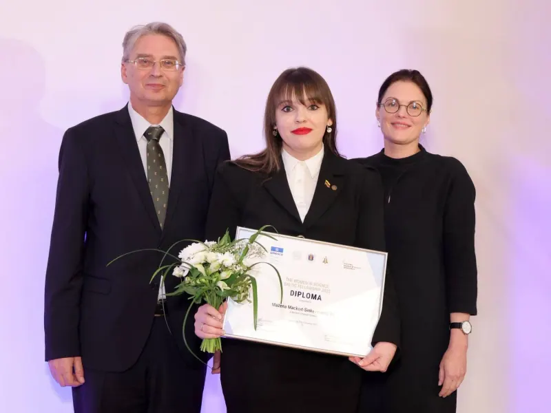 Me holding the diploma and flowers between the two organisers who presented the award