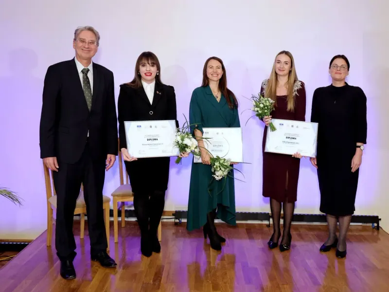 The three fellowship laureates, including me, on stage with diplomas and flowers, next to the organisers who presented the award